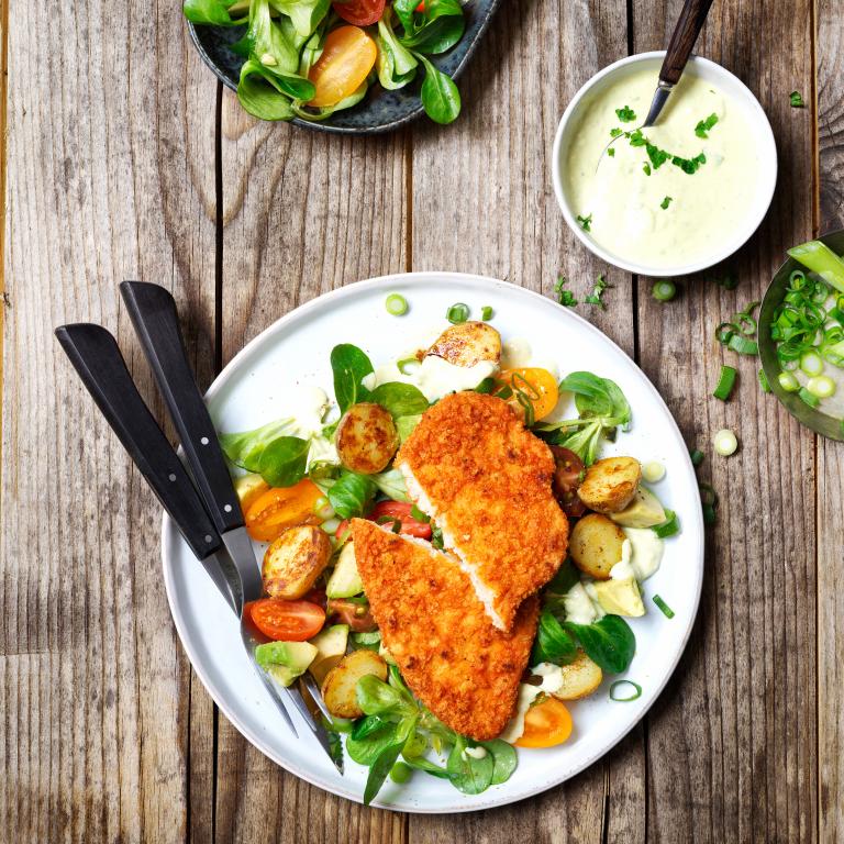 Schnitzel with baked potatoes, tomato salad and avocado dressing